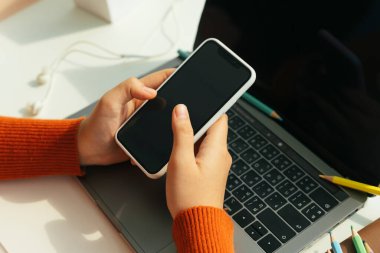 Akıllı telefon ve dizüstü bilgisayarla evden öğrenci çalışması.