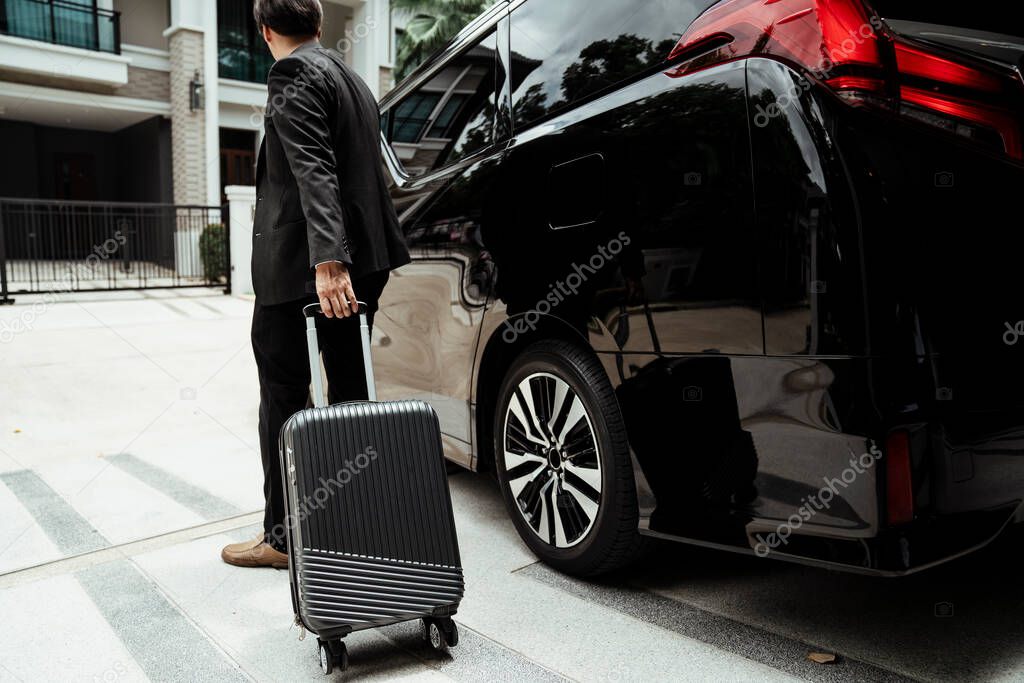 Businessman pulling luggage wheel to a car traveling to airport.
