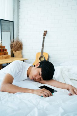 Siyah saçlı adam, yatak odasındaki beyaz yatağa mektup yazarken uyuyakalmış..