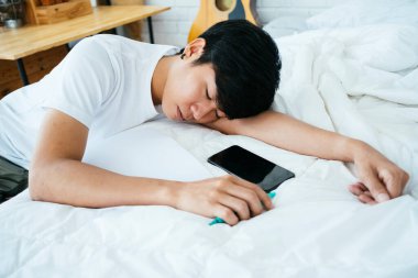 Siyah saçlı adam, beyaz yatağına, yatay olarak mektup yazarken uykuya dalıyor..