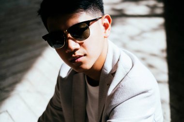 Binanın içinde güneş gözlüklü bir adamın güneş ışığında oturduğu yakın çekim..