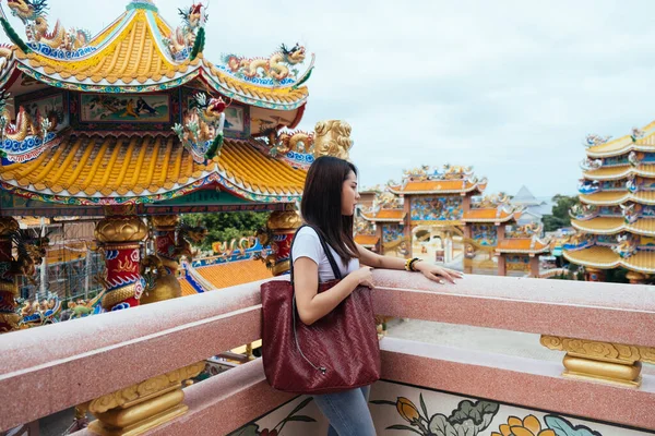 身穿休闲装的长发女人站在寺庙的阳台上 手里拿着红包 — 图库照片