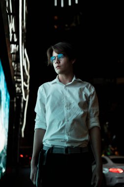 Beyaz tişörtlü ve gözlüklü siyah adam elinde LED ışığı işareti ile restoranın önünde yürümeyi bırak ve akşam yemeği için bir karar ver..