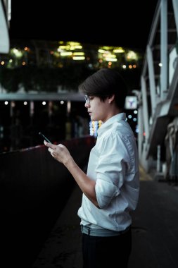 Alış veriş merkezinin önünde elinde LED reklam panosuyla duran siyah saçlı adam haritadaki yerini kontrol etmek için akıllı telefonunu tutuyor..