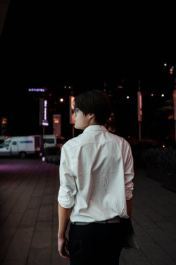 Geceleri elinde dizüstü bilgisayarla şehirde dolaşan beyaz gömlekli bir adam..