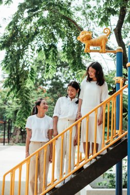 Oyun parkındaki oyuncak merdiveninde duran üçlü ikiz kardeş..