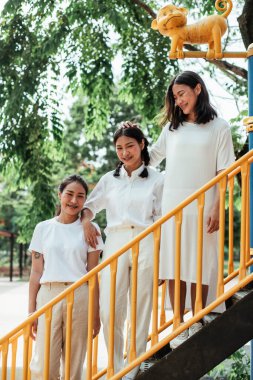 Oyun parkındaki oyuncak merdiveninde duran üçlü ikiz kardeş..