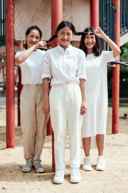 Üçlü ikiz kardeş, parkın oyun bahçesindeki kırmızı kutupta mutlu..