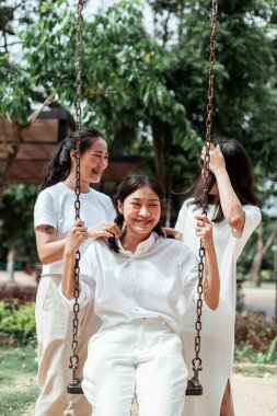 Üçlü ikiz kardeş yazın parkta salıncak oynuyor..