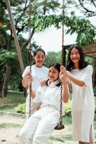 Üçlü ikiz kardeş yazın parkta salıncak oynuyor..