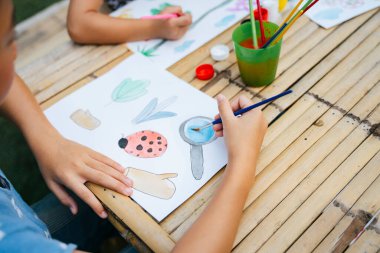 Çocuk boyayı kağıt üzerinde su fırçasıyla boyuyor..