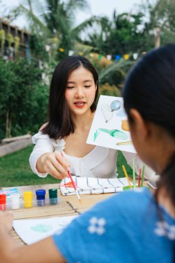 Abla küçük kız kardeşine sulu boya yapmayı öğretiyor..