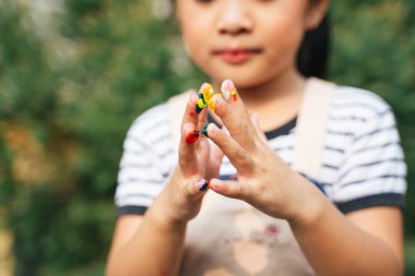 Açık havada parmaklarıyla oynayan sevimli Asyalı küçük kızın ellerini kapat..