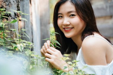 Doğada beyaz elbise giymiş güzel Asyalı bir kadının portresi. Mutluluk ifadesiyle gülümsüyor.