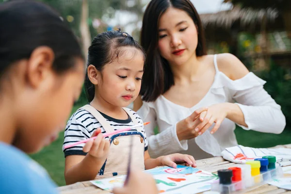 アジアの姉ヘルプ小さな妹絵画水色上の紙屋外 — ストック写真