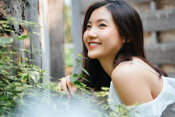 Doğada beyaz elbise giymiş güzel Asyalı bir kadının portresi. Mutluluk ifadesiyle gülümsüyor.