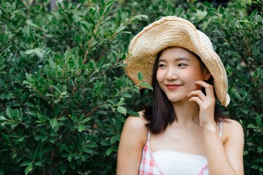 Asyalı bir kadın, yeşil yaprağın yanında, canlı duvarda duruyor. Çevre yolculuğu.