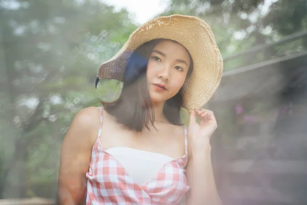 ピンクのドレスに美しい若いアジアの女性は 自然の中で大きな帽子の旅行を着て トラベル 蒸気の後ろに立って — ストック写真