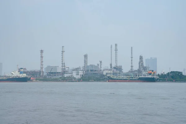 Industrial Estate on Chao Phraya River, Thailand. Industrial view at oil refinery plant form industry zone with cloudy sky at the Chaophaya river in Bangkok Thailand. Smog all over the city. Pollution day.