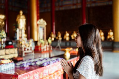 Tapınakta dua eden Taylandlı kadın. Tayland 'daki Buda heykeline saygılarını sunan Asyalı kadın..