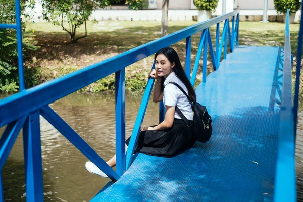 Černé Dlouhé Vlasy Vysoká Škola Dívka Uniformě Sedí Modrém Mostě — Stock fotografie