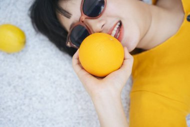 Turuncu gözlük takan kadın portresi. Yaz tatili. Sağlıklı meyve sever..