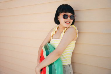 Bob saç kesimi, sarı kolsuz bluz ve güneş gözlüğü takan güzel Asyalı kadın can simidiyle poz veriyor ya da yüzüyor..