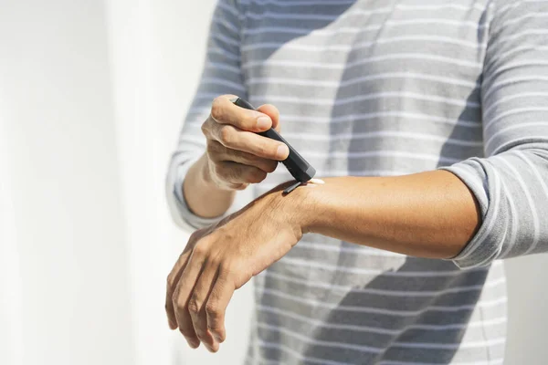 Hand of a man applying cream lotion on arms to protect the skin from UV sunlight. Solar protection. Sunblock lotion bottle. Sun Screen protection on man hand.