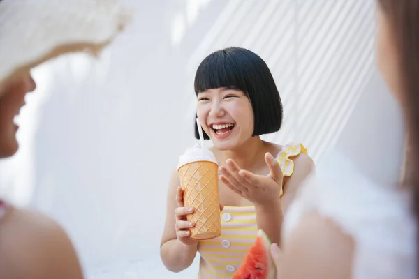 Bob hairstyle cute asian woman talking with friend while drinking juice from plastic bottle.