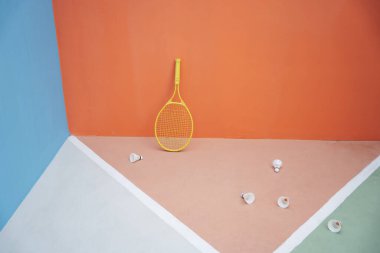 Renkli arka plan ve sarı tenis raketi. Yerde bir sürü mekik horozu var. Spor arkaplanı. 