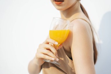 Çekici, güzel esmer kadının portresi. Beyaz arka planda izole edilmiş cam bardakta portakal suyu içiyor..