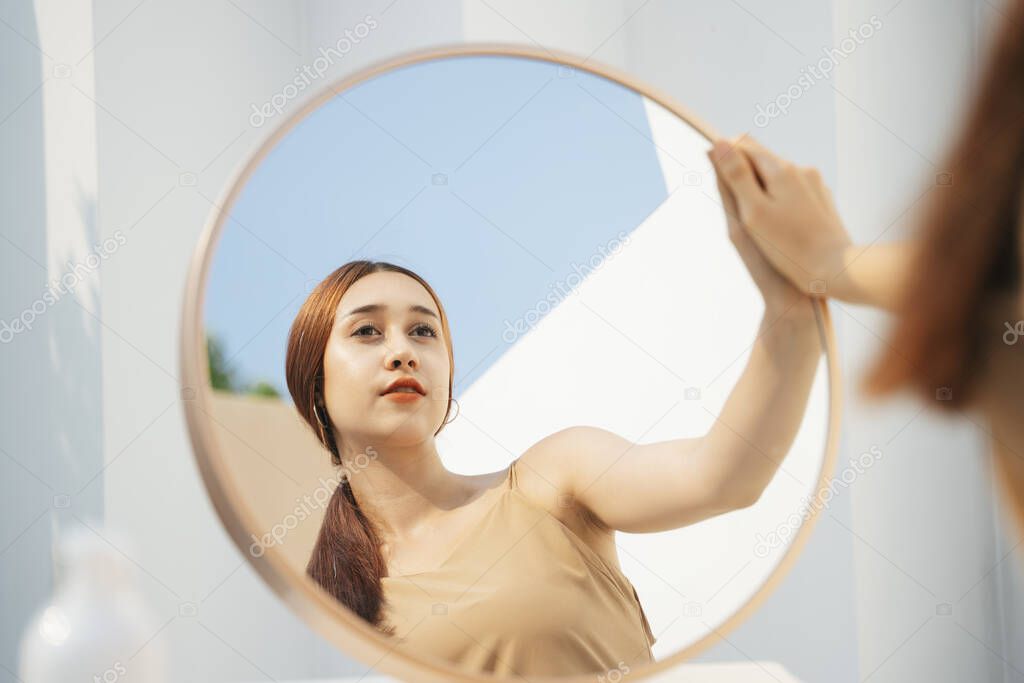 Attractive beautiful brunette woman applying cosmetic in front of the mirror. Cosmetic concept.