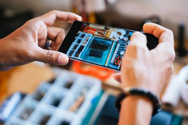 Ustabaşının el yapımı deri cüzdanının fotoğrafını çekmek için kullandığı akıllı telefonun kesilmiş görüntüsü..