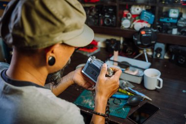 Bir adam kamerayı tamir eder, objektifteki tozu temizler ve bütün parçaları bir araya getirir..