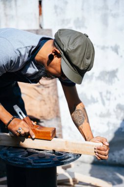 Sanatçılar kalası ölçüp inceltmek için tıraş aletini kullanırlar..