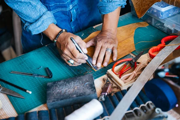 Cropped image of leather on the cutting mat while the craftsman try to cut it.