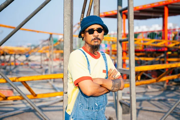 Man Yellow Shirt Denim Overalls Standing Abandoned Amusement Park Sunny — Stock Photo, Image