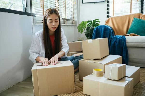 Long hair woman pack the goods into the parcel for online order, alone in her house.