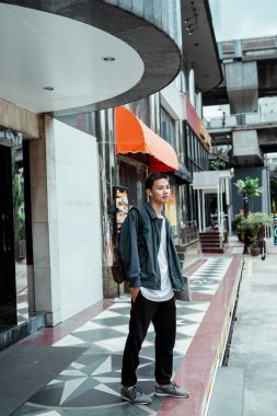 Kısa saçlı adam, müşteriyle görüştükten sonra binanın önünde dizüstü bilgisayar tutuyor ve bisikleti bekliyor..