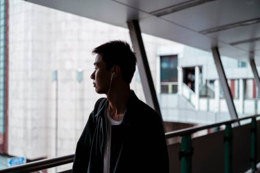 Kulaklıklı adamın siluet fotoğrafı. Gökyüzünde dikilip merdivenlerden aşağıya bakan adam..