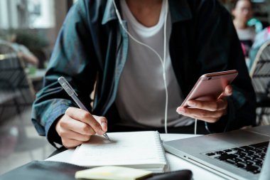Kesilmiş akıllı telefon iamge adam tarafından tutulur o kafede çalışırken ve müzik dinleme.