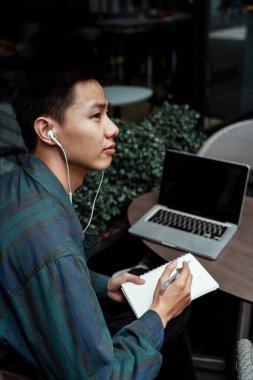 Kısa saçlı adam, kafenin terasında otururken işinin çözümünü düşünüyor..