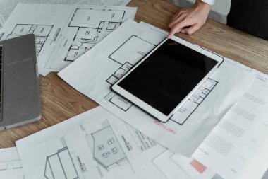 Tabletin köşesinde indeksi olan yemekhane masasındaki basılı planda kesilen tabletin resmi.