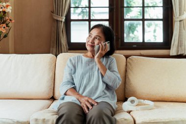 Asyalı son sınıf öğrencisi bir kadın, çocuklarını aramak ya da müzik dinlemek için akıllı telefon kullanıyor..