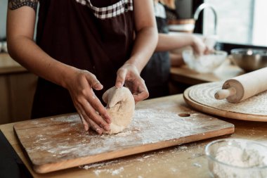 Kadın pasta şefi mutfakta ekmek hamuru yoğuruyor. Un ve tereyağlı yemek yapmak. Ellerle ekmek hamuru yapmayı. Yemek pişirme prosedürü.