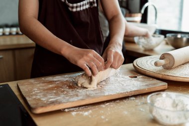 Kadın pasta şefi mutfakta ekmek hamuru yoğuruyor. Un ve tereyağlı yemek yapmak. Ellerle ekmek hamuru yapmayı. Yemek pişirme prosedürü.