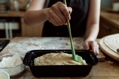 Hamur işi şefi ekmek hamurunu ekmek kalıbıyla fırçalıyor..