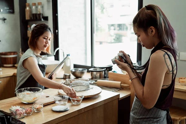 Young asian baker women doing cooking show recording video with camera. Cooking Vlog by LGBTQ people in the kitchen. Making bread. Cheerful two asian baker women making bread dough.