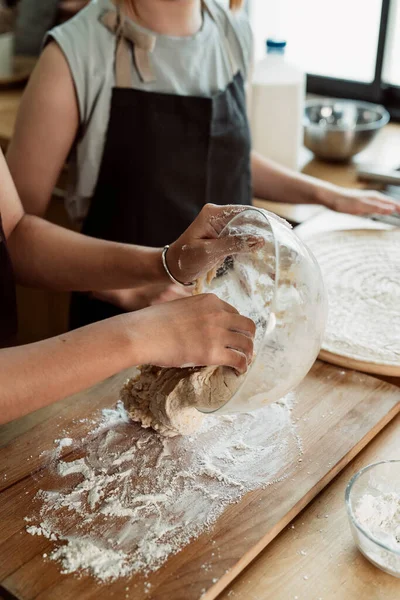 Asian baker woman let the dough out of glass bowl rest on the wooden plate.