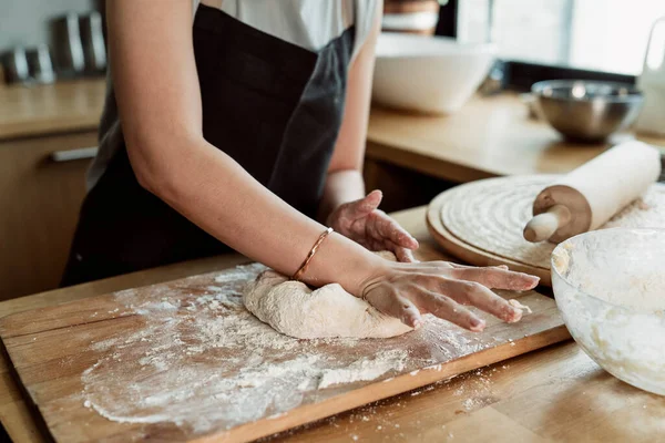 Cheerful pastry woman kneading bread dough. Asian young woman threshing bread dough with rolling pin on worktop.